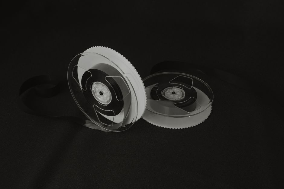 Close-up of vintage cassette tape reels on a black background, illustrating nostalgia and retro vibes.