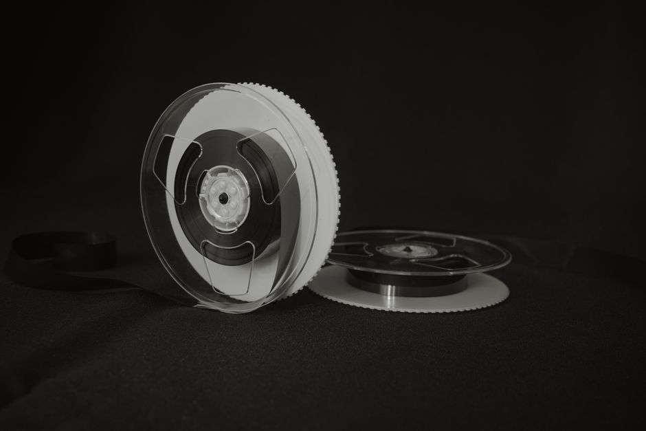 Close-up of a vintage reel-to-reel audio tape on a black background, showcasing retro recording technology.